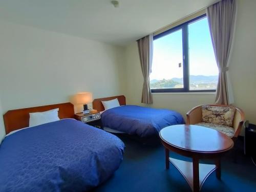 a hotel room with two beds and a table and a window at Inuyama City Hotel in Inuyama