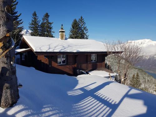 uma casa coberta de neve com uma sombra de uma cruz em Burehüsli Axalp em Axalp