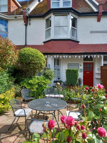 una mesa y sillas frente a una casa con rosas en Belle Dene Guest House, en Paignton