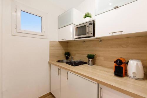 une cuisine avec des armoires blanches, un évier et un micro-ondes dans l'établissement Studio au calme, avec terrasse et parking à Eze village, à Èze