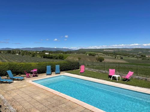 a swimming pool with pink and blue chairs next to at La Ferme l'Etang in Vachères