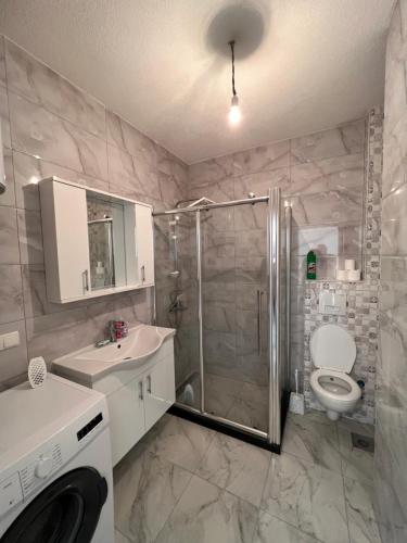 y baño con ducha, aseo y lavamanos. en Cosy Apartment with a Great View en Pristina