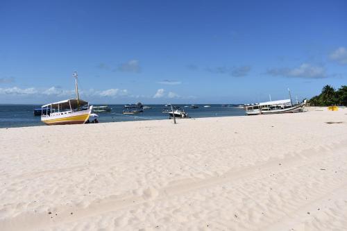 a sandy beach with boats in the water at La casa de Luna in Guaibim