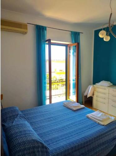 a bedroom with a blue bed and a window at Appartamento Le Margherite in Procida