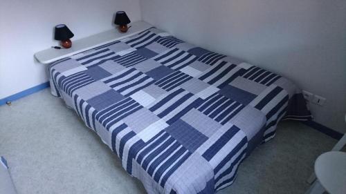 ein Bett mit einer blauen und weißen Bettdecke in einem Schlafzimmer in der Unterkunft Loudenvielle résidence l'Orée des Monts in Loudenvielle