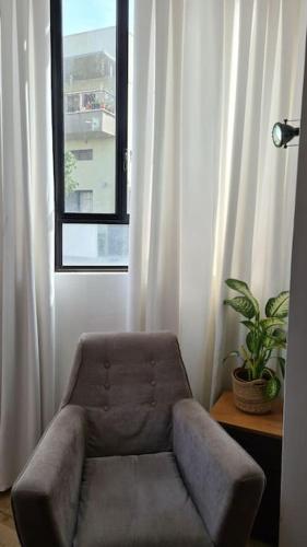 a brown chair in a room with a window at Bright Studio in Shapira in Tel Aviv