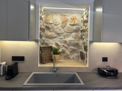 - une cuisine avec un évier et un mur en pierre dans l'établissement Piedra Luxury Apartments, à Nauplie