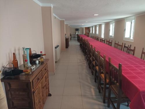 een lange rij tafels in een kerk met rode tafelkleden bij Hotel Villa Jardín in Portomarin