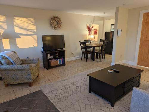 a living room with a couch a table and a tv at Waterfront ground floor condo Sheepscot Harbour Vacation Club 1 Bedroom Condo #205 in Edgecomb