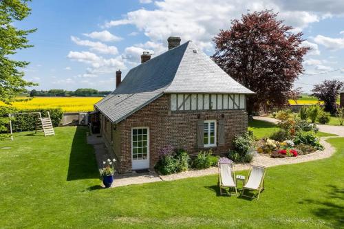 a small brick house with two chairs in the yard at Cottage 4 chambres avec cheminée in Épégard
