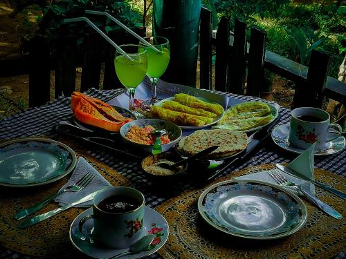 a table with plates of food and glasses of wine at Village feel home stay in Sigiriya
