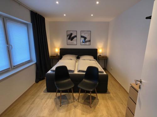 1 dormitorio con 1 cama y 2 sillas en Luxuriöse Ferienwohnung in Chemnitz - Apartment B28 für 2 plus 2 Gäste en Chemnitz