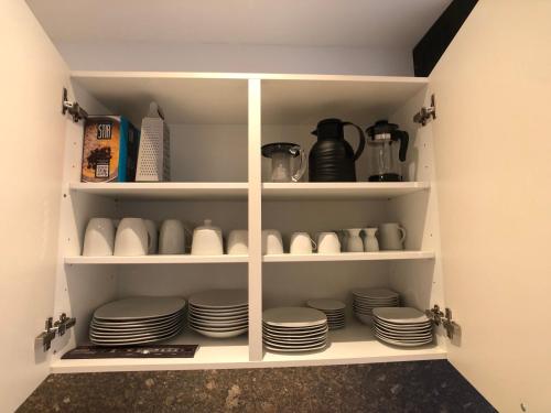 a cupboard with plates and cups in it at Luxuriöse Ferienwohnung in Chemnitz - Apartment B28 für 2 plus 2 Gäste in Chemnitz