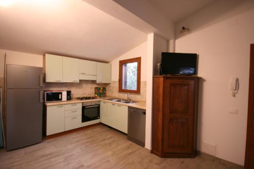 a kitchen with white cabinets and a refrigerator at Casetta sulla Bolgherese immersa nel Verde in Castagneto Carducci
