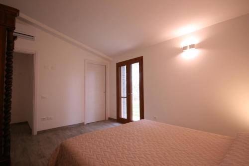 an empty bedroom with a bed and a window at Casetta sulla Bolgherese immersa nel Verde in Castagneto Carducci