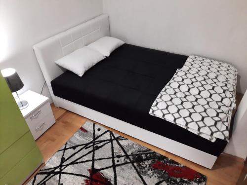 Cama en habitación con edredón blanco y negro en Victory apartment, en Niš