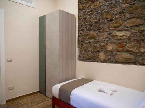 a bedroom with a bed and a stone wall at Sicilia Bedda - B&B - Rooms - Apartments in Santo Stefano di Camastra