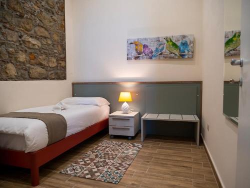 1 dormitorio con 1 cama y 1 mesa con lámpara en Sicilia Bedda - B&B - Rooms - Apartments, en Santo Stefano di Camastra
