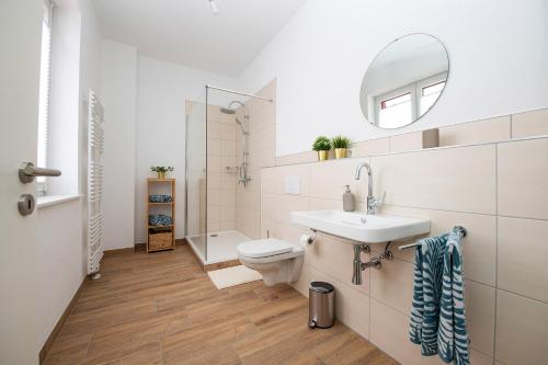 W łazience znajduje się umywalka, toaleta i lustro. w obiekcie Villa Kaliva w mieście Bullay