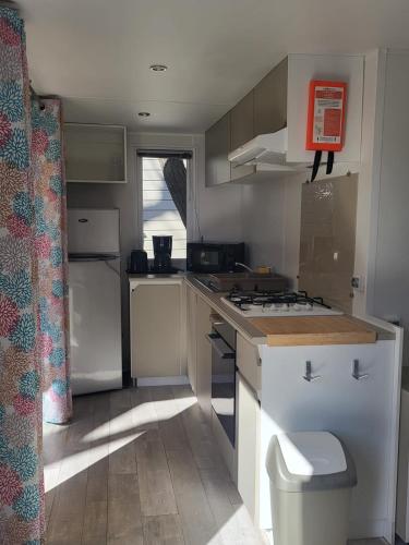 Il comprend une petite cuisine équipée d'une cuisinière et d'un évier. dans l'établissement Mobil home Camping La Marine, au Grau-du-Roi