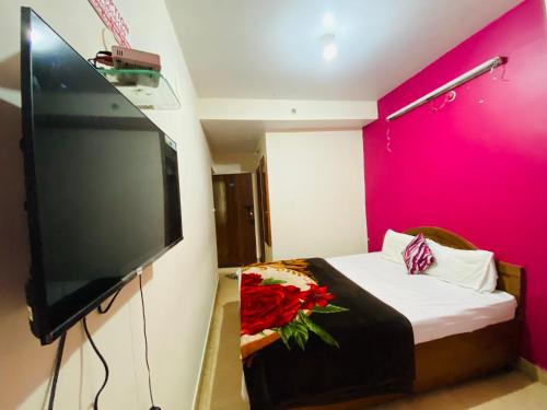 a bedroom with a large flat screen tv and a bed at Hotel Nakshatra in Ooty