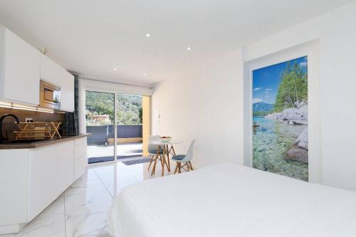 a white bedroom with a kitchen and a large window at Studio tout confort avec parking et terrasse à Eze village in Éze