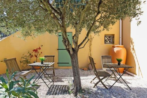 a group of tables and chairs next to a tree at Studio tout confort avec parking et terrasse à Eze village in Éze