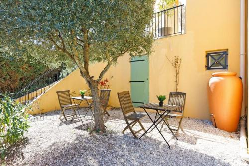 a patio with chairs and a table and a tree at Studio tout confort avec parking et terrasse à Eze village in Éze