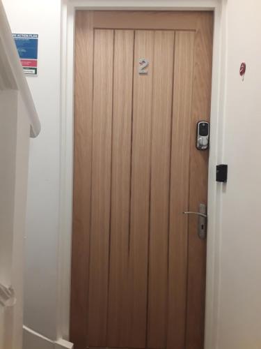uma porta de madeira numa casa de banho ao lado de um WC em Jaskar studio 2 em Cheltenham