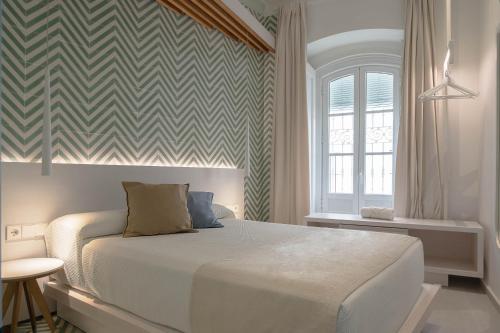 a bedroom with a bed in a room with a checkered wall at La Casa del Arco in Conil de la Frontera