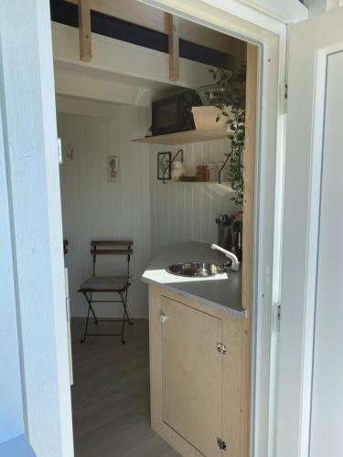 uma cozinha com um lavatório e um balcão com uma cadeira em Kroghs Tiny Houses - Hyttebyen em Grindsted