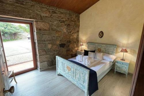 a bedroom with a bed and a stone wall at Lugar encantador com estacionamento incluído in Reboreda