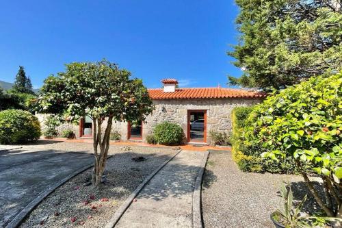 a stone house with a tree in front of it at Lugar encantador com estacionamento incluído in Reboreda