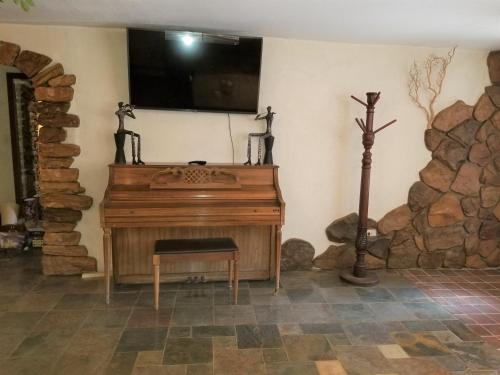 un pianoforte in legno in una stanza con un muro in pietra di Your comfy home in Colorado Springs a Colorado Springs