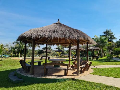 um pavilhão com uma mesa e cadeiras e um guarda-sol de relva em Granja Mi Retiro em Areguá