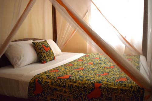 ein Bett mit einer Bettdecke und Kissen im Schlafzimmer in der Unterkunft Zanzibar Dream Lodge in Bwejuu