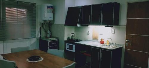 a small kitchen with a wooden table and a sink at departamento centrico de un dormitorio para tres personas in San Juan