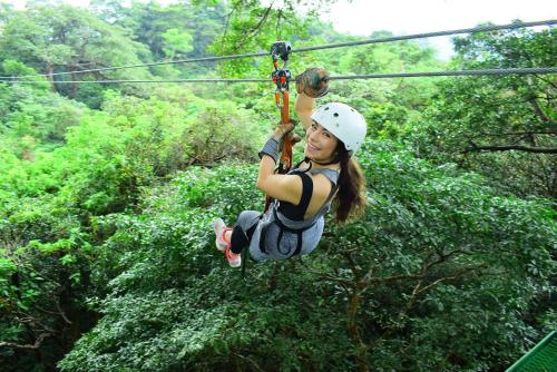 a woman on a zip line in the forest at Buena Vista del Rincón Eco Adventure Park Hotel & Spa in Liberia
