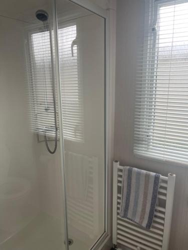 a bathroom with a shower and a towel on a chair at MV18 Park Holidays, St Osyth Beach no smoking self catering holiday in Saint Osyth