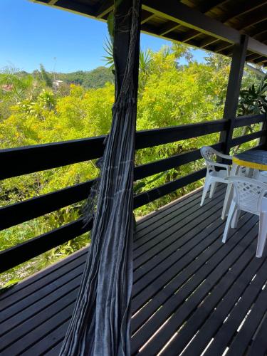 a tree on a deck with a table and chairs at Morada Crisálida in Praia do Rosa