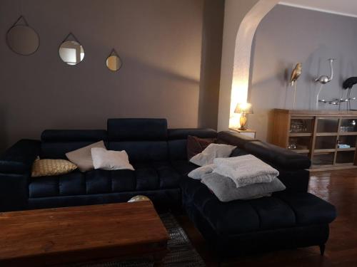 ein Wohnzimmer mit einem schwarzen Sofa und einem Tisch in der Unterkunft Le repos bien mérité in Nesle