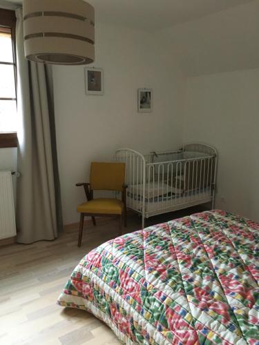 a bedroom with a crib and a chair at villa des cascades du hérisson in Bonlieu