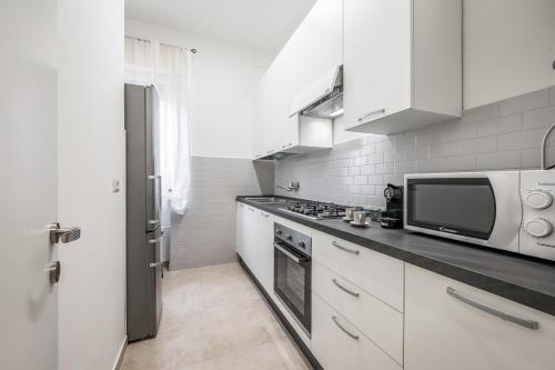 a white kitchen with a microwave and a stove at Casa Amelia - Elegant Suite con parcheggio gratuito in Parma