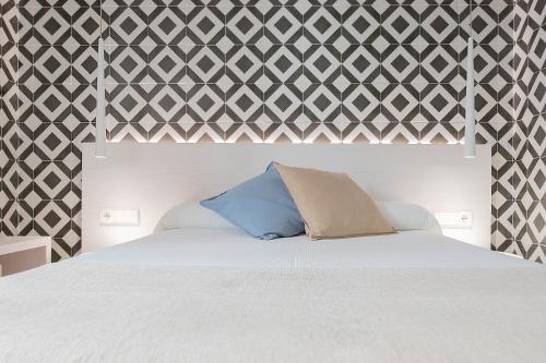 a bedroom with a white bed with a geometric accent wall at La Casa del Arco in Conil de la Frontera
