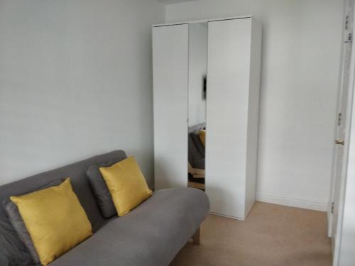 sala de estar con sofá gris y almohadas amarillas en Lanhydrock View en Bodmin