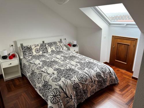 Un dormitorio con una cama en blanco y negro y una ventana en ATICO muy luminoso e increíbles vistas en Baiona