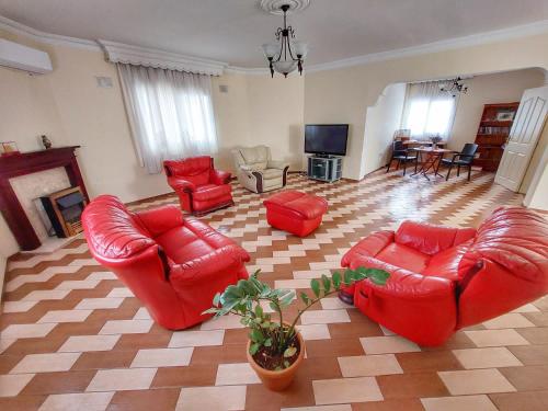 a living room with red leather chairs and a television at Glapsides Sea Villa in Famagusta