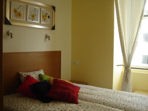 um quarto com uma cama com almofadas e uma janela em Baixasuites em Lisboa