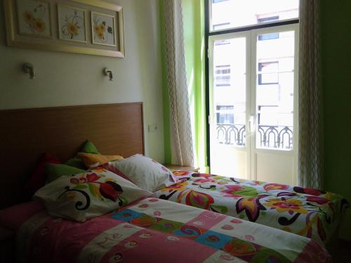 a bedroom with a bed with a window and a bedspread at Baixasuites in Lisbon