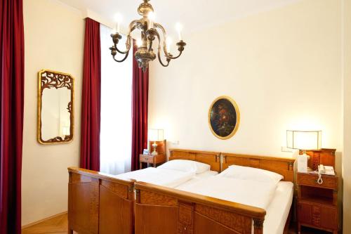 a bedroom with a bed and a chandelier at Graben Hotel in Vienna